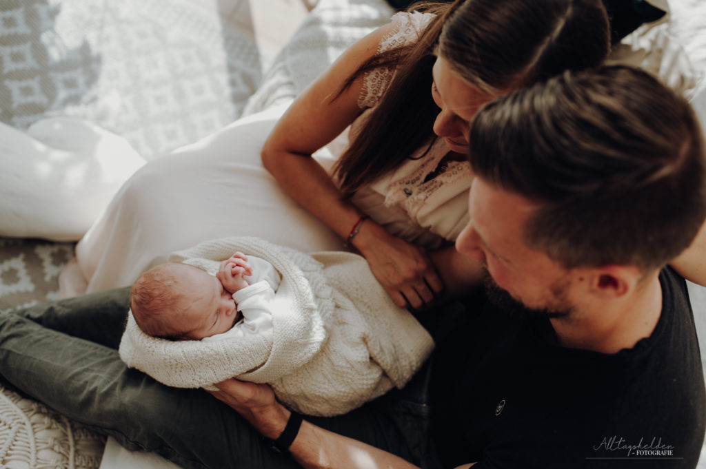 glückliche Eltern halten das Baby
